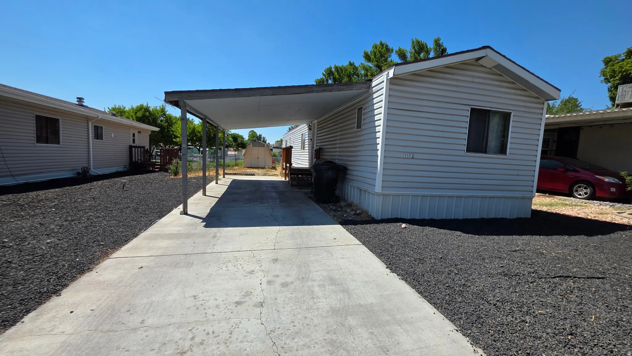 Manufactured home featuring a concrete driveway, covered carport, and metal roof structure