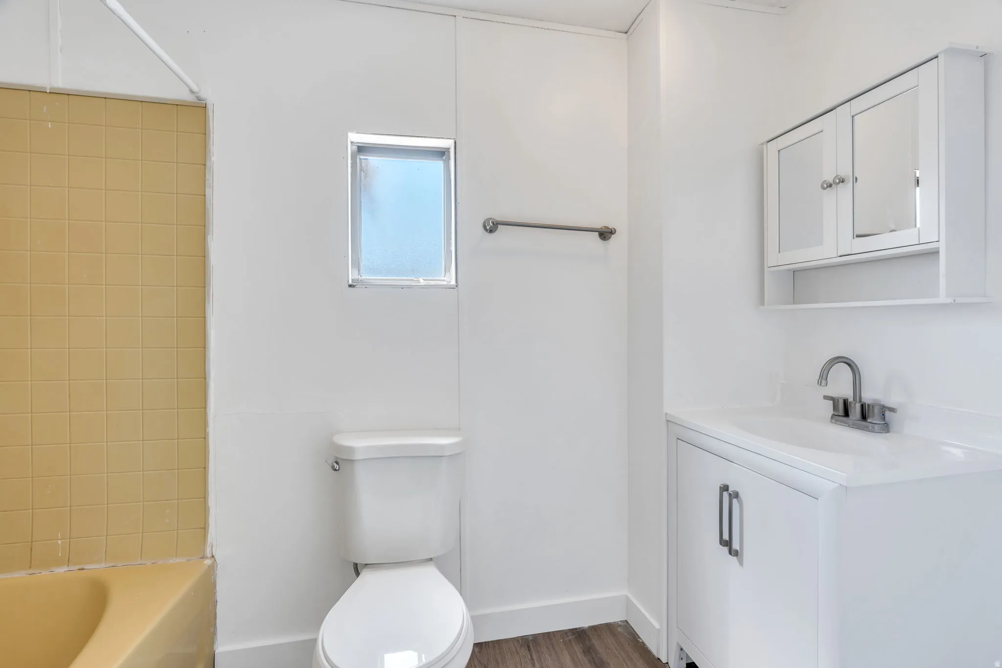 White vanity with integrated sink, chrome faucet, and mirrored medicine cabinet