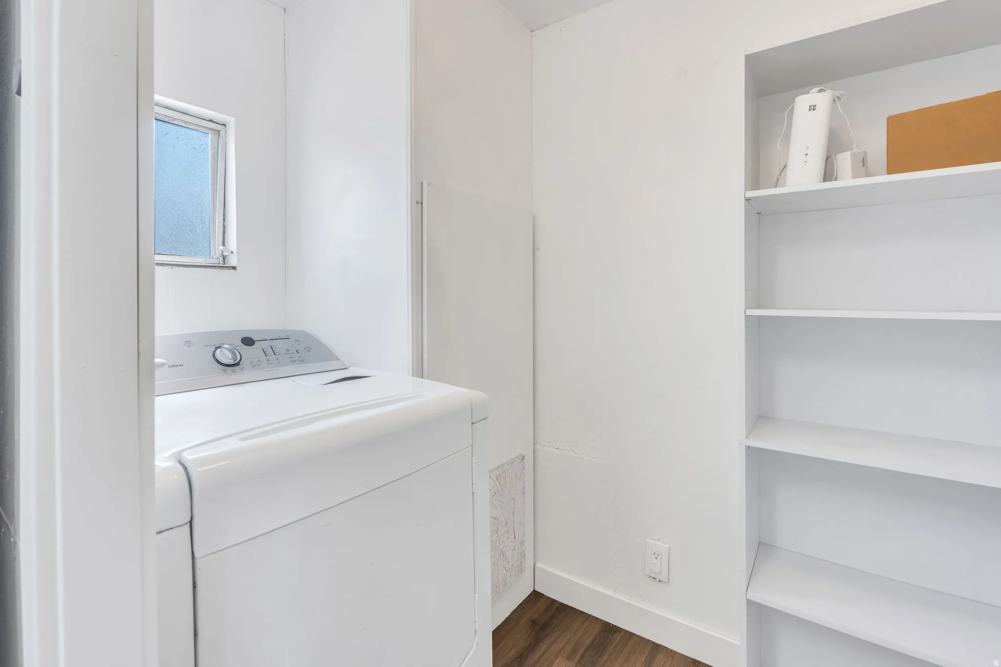 Laundry area featuring a window, built-in shelving, and wood-finish flooring