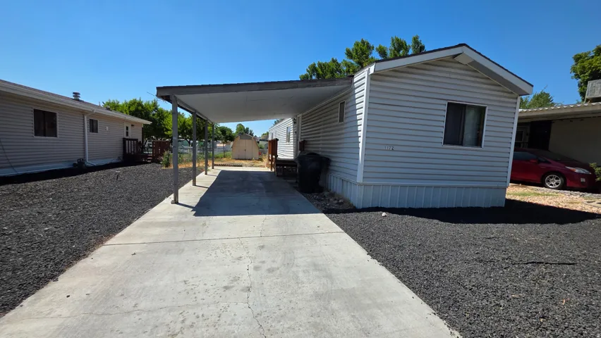 Manufactured home featuring a concrete driveway, covered carport, and metal roof structure