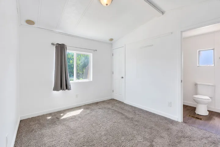 Carpeted flooring, white walls, and a window providing natural illumination