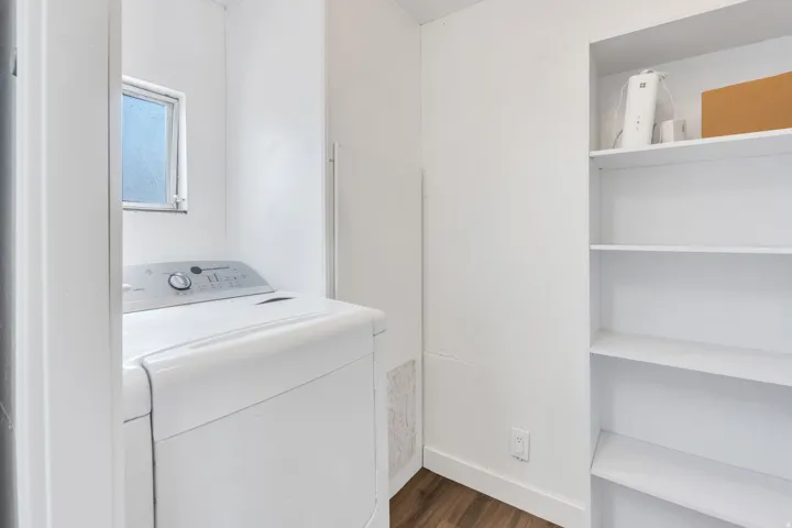 Laundry area featuring a window, built-in shelving, and wood-finish flooring