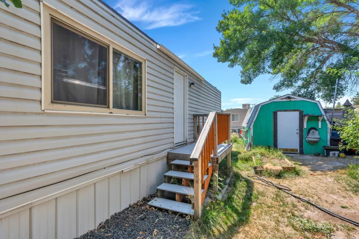 Exterior featuring horizontal siding, a wood deck with railings, and a separate storage shed with a white door