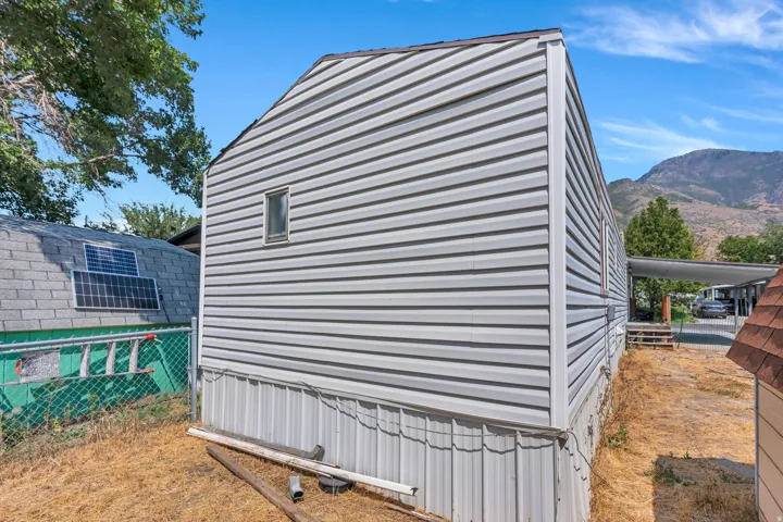 White horizontal siding exterior with a single window and mountains in the background