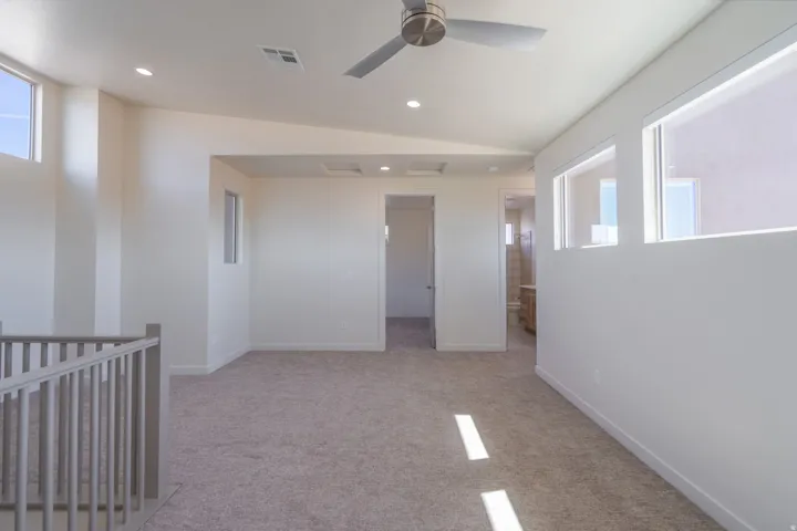 Bright, open room featuring abundant natural light from multiple high windows, neutral carpet flooring, and recessed ceiling lighting