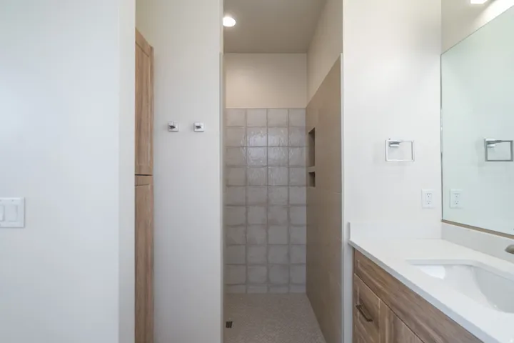 Walk-in shower with tiled walls and floor, featuring a built-in shower niche
