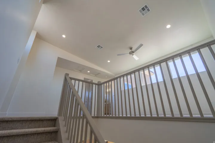 Staircase with carpeted treads and light-toned railings featuring vertical balusters