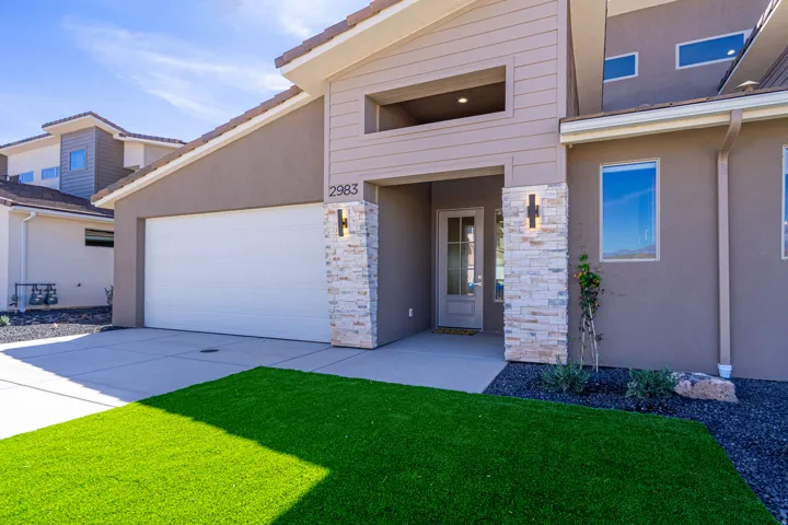 Contemporary exterior featuring stucco siding, stone accents, and an integrated two-car garage