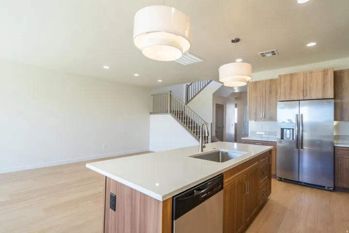Open-concept kitchen featuring an island with an undermount sink and stainless steel dishwasher