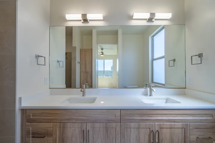Double vanity featuring wood-finish cabinetry, white countertops, dual integrated sinks, and brushed nickel fixtures