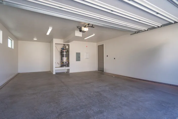 Spacious garage with concrete flooring, recessed lighting, and a water heater enclosure