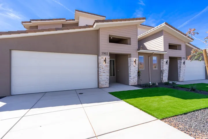 Contemporary facade featuring a neutral color palette, stone veneer accents, and multiple garage doors