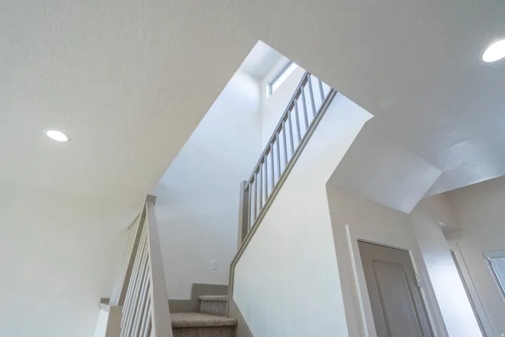 Staircase featuring carpeted steps and painted wood balusters