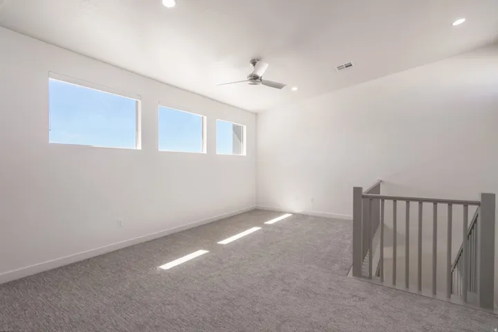 Spacious room featuring three horizontal windows, recessed lighting, and a ceiling fan