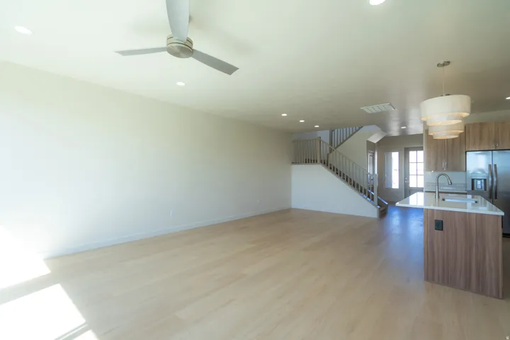 Spacious open-concept living area featuring light wood-finish flooring, recessed lighting, and a contemporary ceiling fan