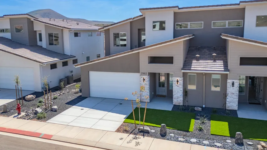 Modern exterior featuring a light gray and warm taupe facade, stone accents, and varied rooflines