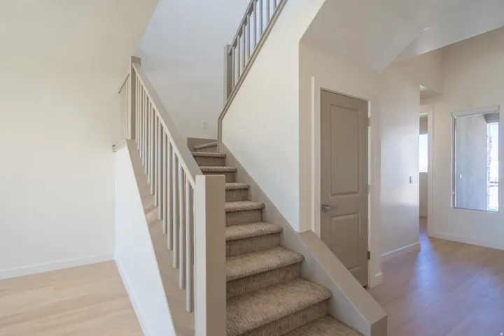 Carpeted staircase with light gray balusters and handrail