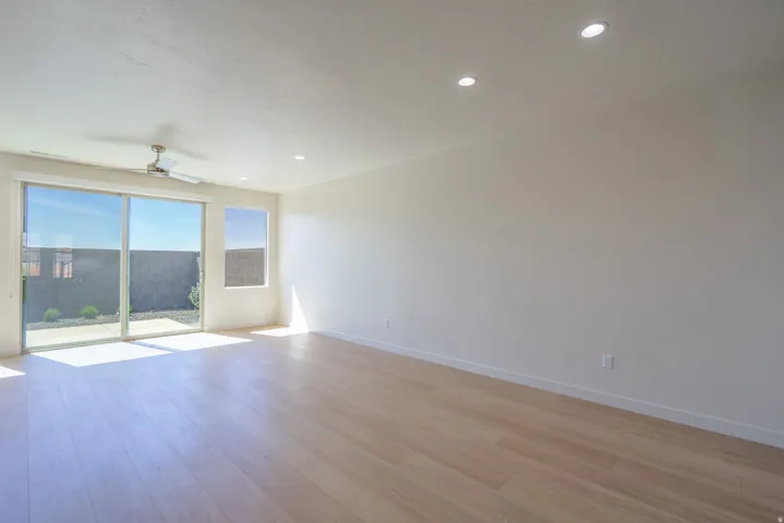 Spacious living area featuring light wood-finish flooring, recessed lighting, and a ceiling fan