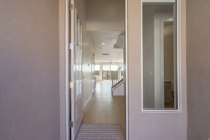 Entryway with a glass-paneled door, light wood-finish flooring, recessed lighting, and a contemporary staircase with metal railings