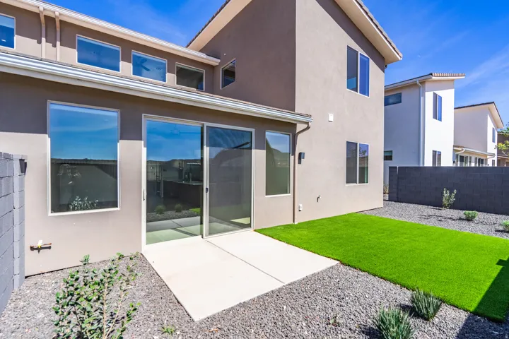 Rear exterior featuring a concrete patio, sliding glass door, and a strip of artificial turf