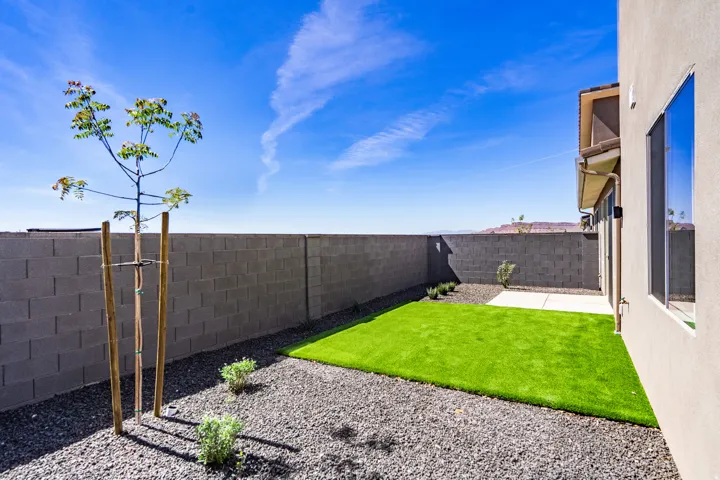 Private backyard featuring a block wall surround, artificial turf, and gravel landscaping