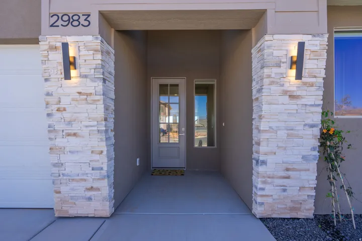 Stone-clad columns frame the entryway, featuring modern exterior lighting fixtures