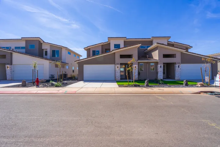Modern multi-story exterior featuring a neutral color palette, stone accents, two-car garages, and a neatly landscaped front yard