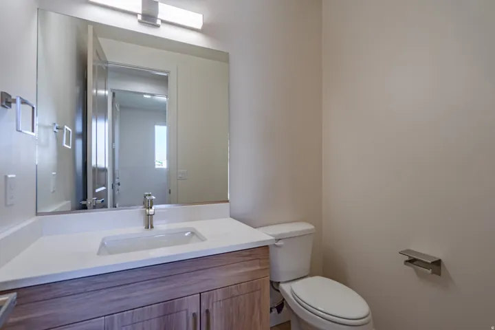 Bathroom featuring a wood-finish vanity with a white countertop and undermount sink, brushed nickel faucet, and a large wall-mounted mirror