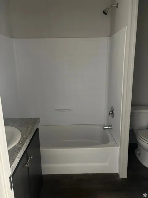 Updated Master Bath featuring a sleek white tile surround with integrated tub/shower combination, chrome fixtures, and a granite-topped vanity with dark cabinetry