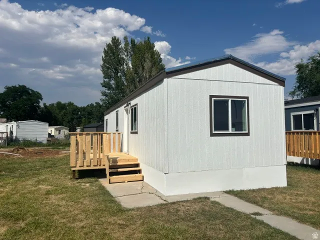 White vertical siding exterior with contrasting dark trim and a dark roof