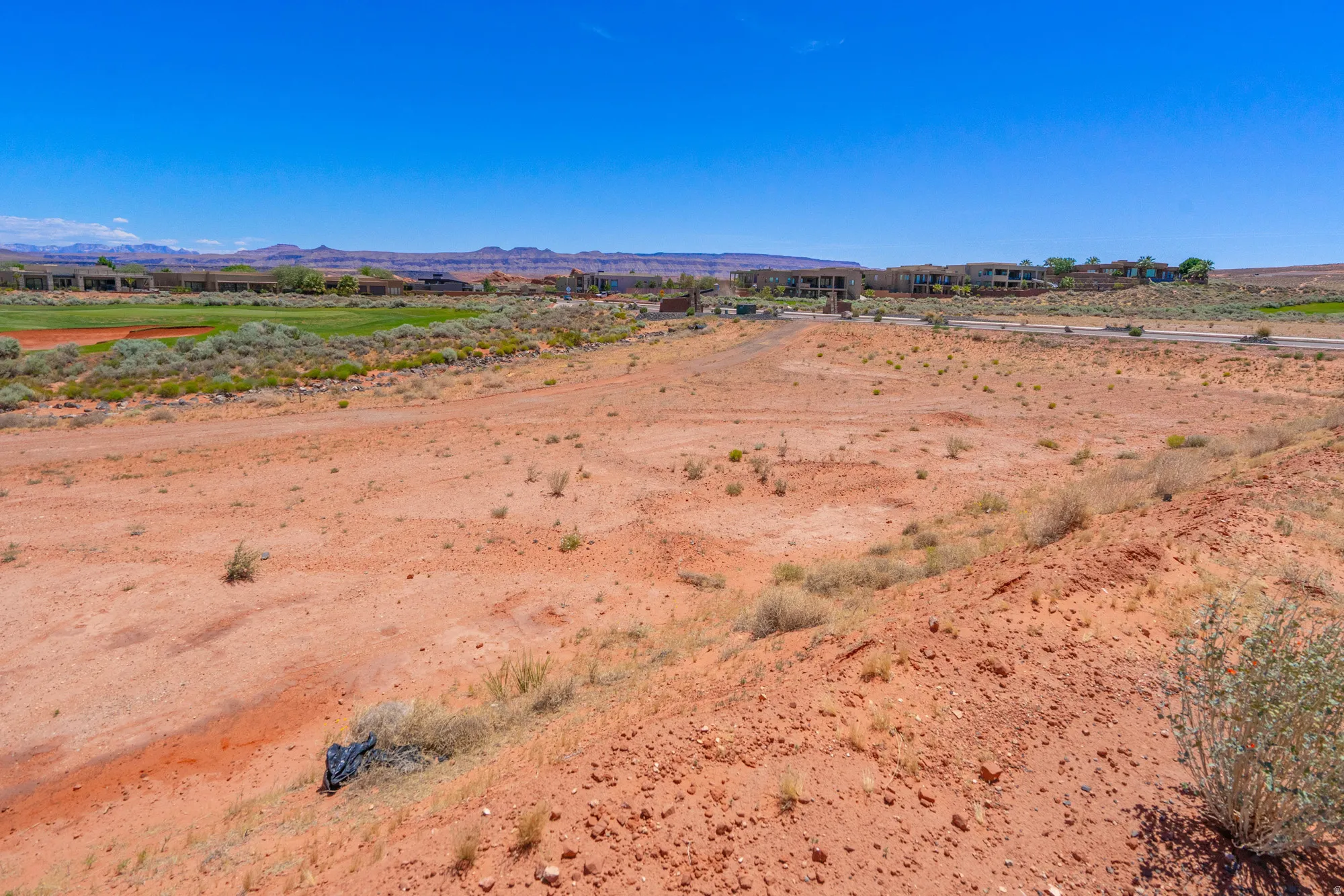 Expansive vacant land featuring red soil composition with sparse native vegetation and natural drainage patterns