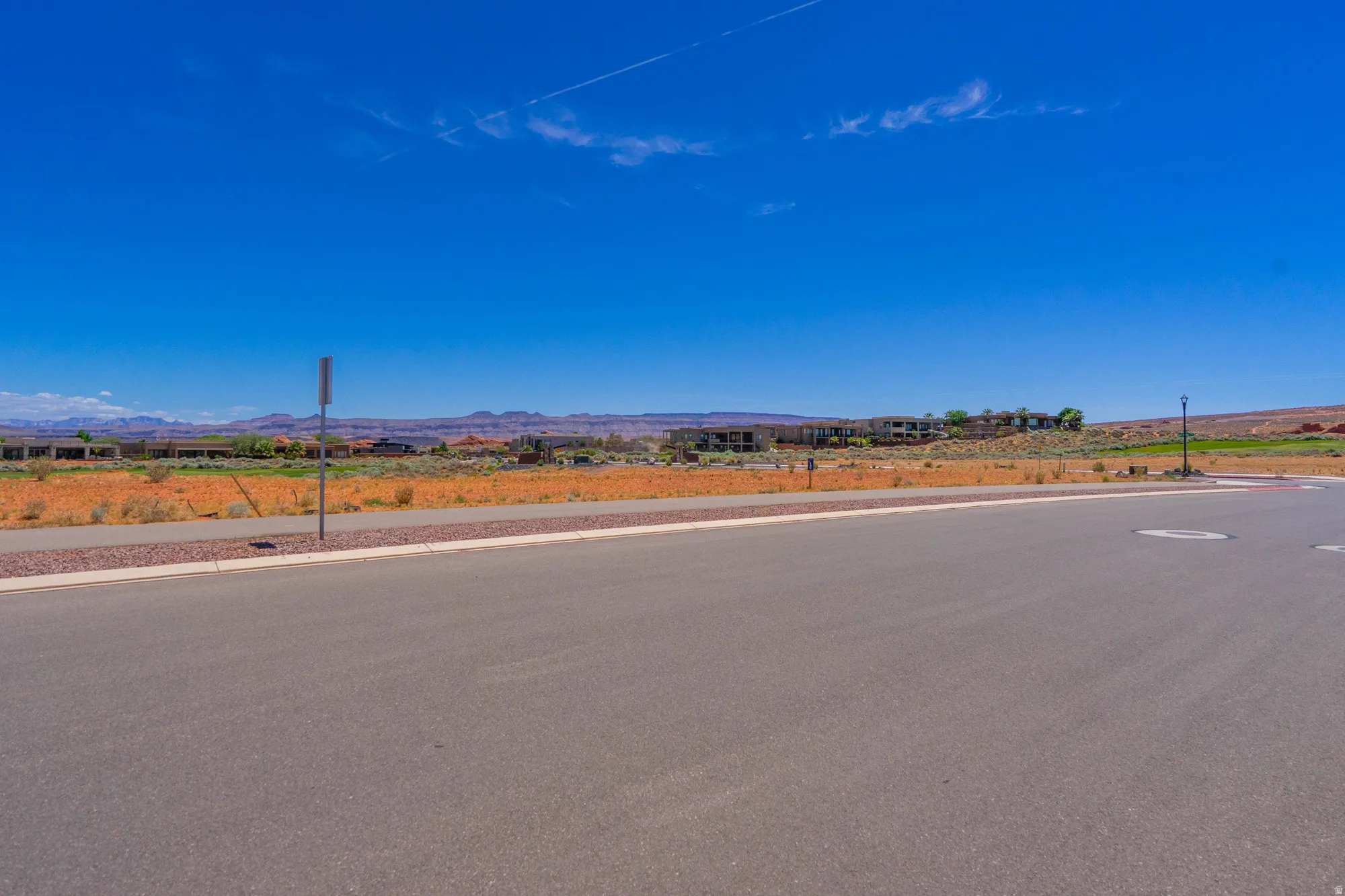Vacant residential lot with paved frontage and clear sightlines to distant mountain ranges