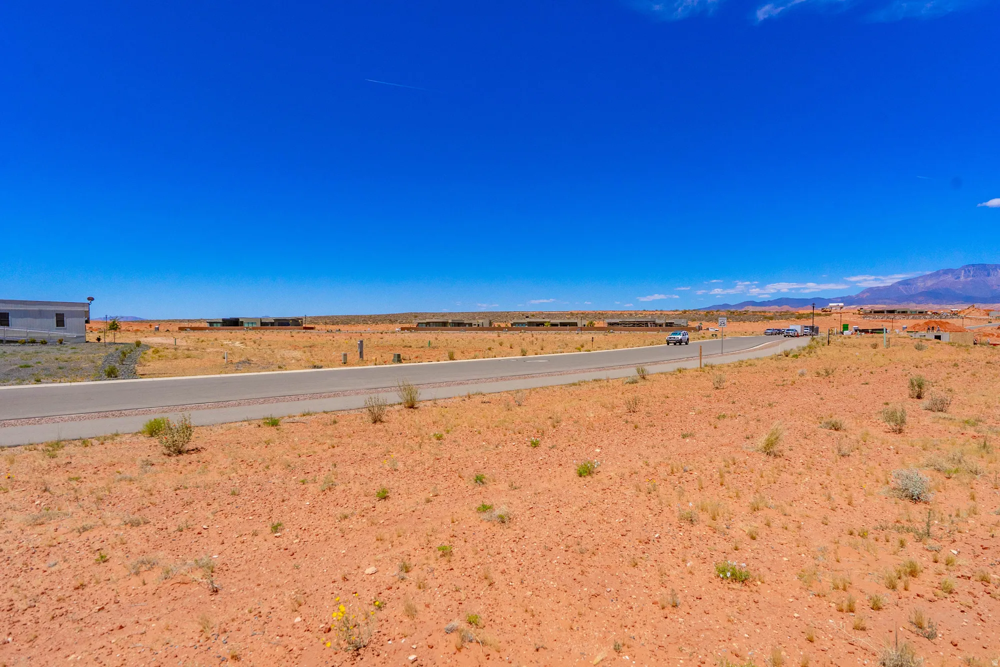 Expansive desert lot featuring direct road frontage, level terrain, and panoramic vistas across open landscape