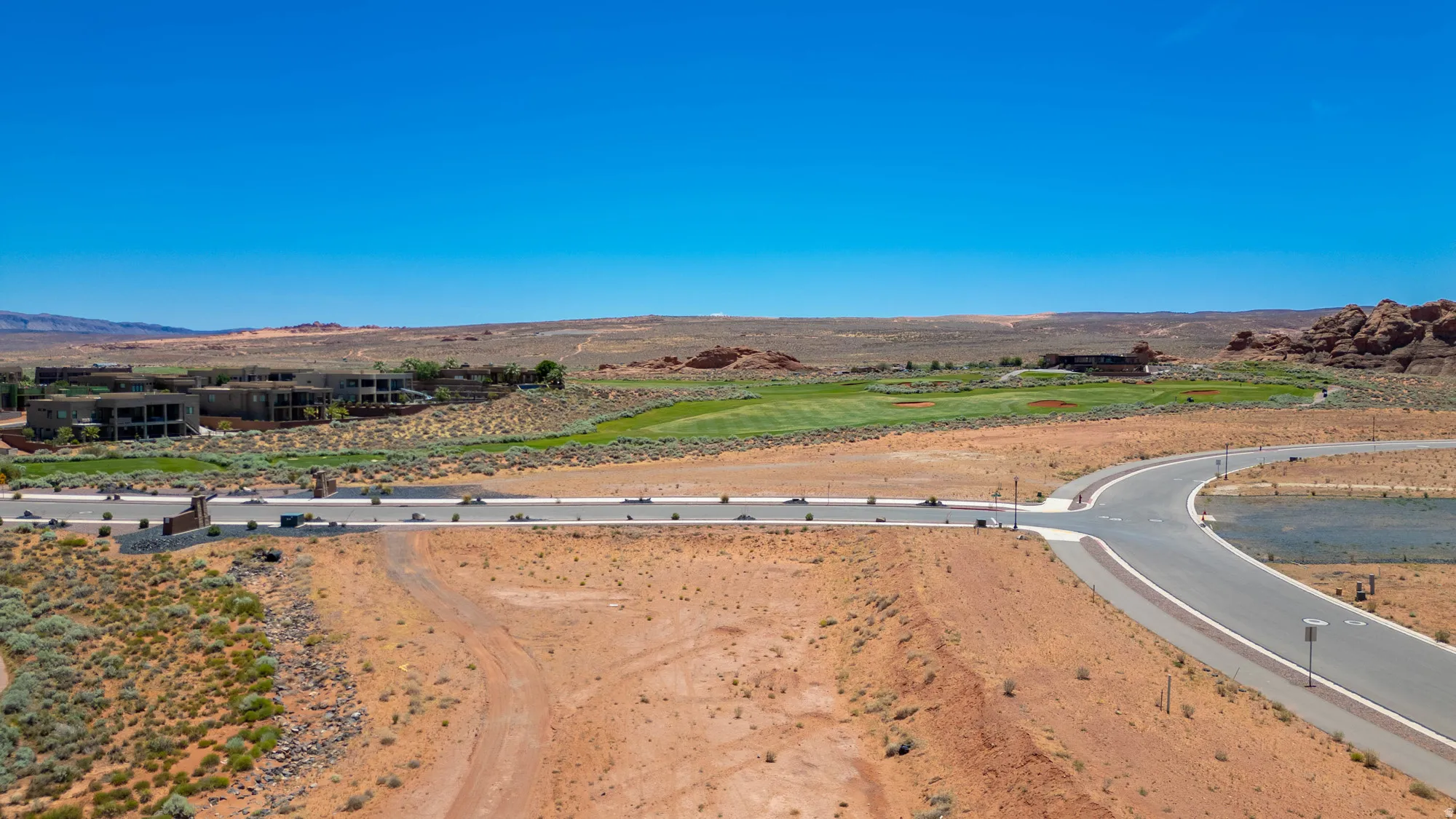 Open desert terrain with paved roads and a distant golf course
