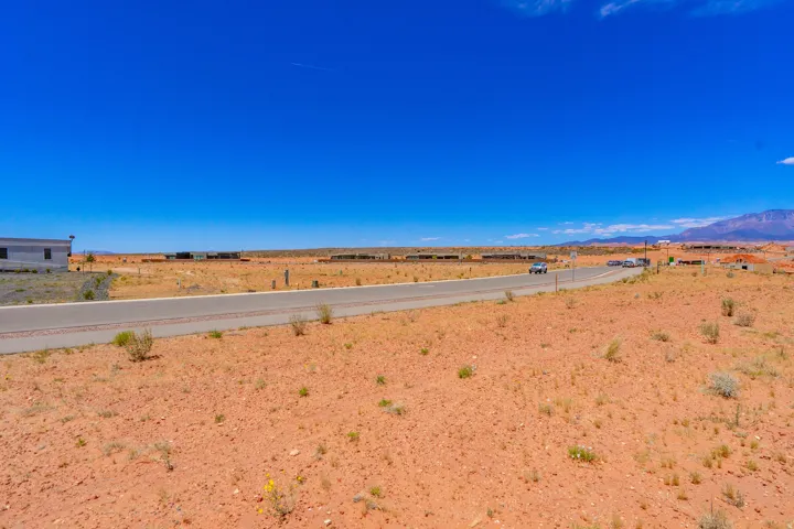Expansive desert lot featuring direct road frontage, level terrain, and panoramic vistas across open landscape