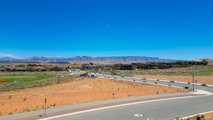 Expansive desert landscape featuring a paved street and distant golf course