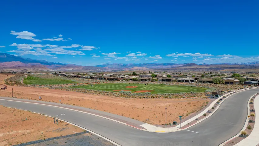 Expansive land parcel featuring newly constructed modern roadway access, mature agricultural cultivation across the property, and panoramic vistas of distant mountain ranges and valley terrain