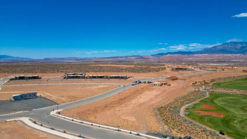 Expansive vacant land featuring newly constructed concrete roadway with professional landscaping infrastructure, manicured turf sections, and prepared development parcels