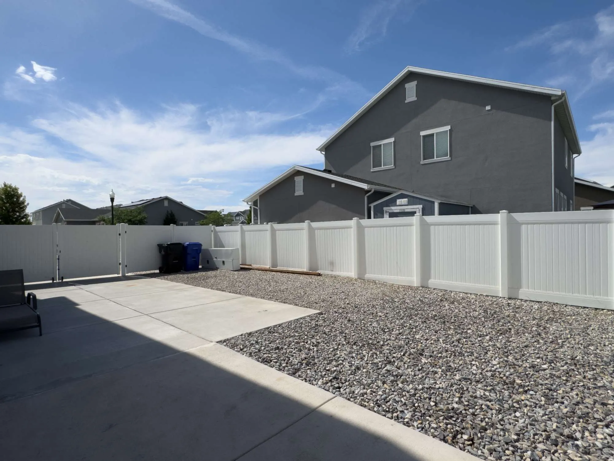 Expansive outdoor area featuring a concrete RV pad and a white privacy fence with a gate