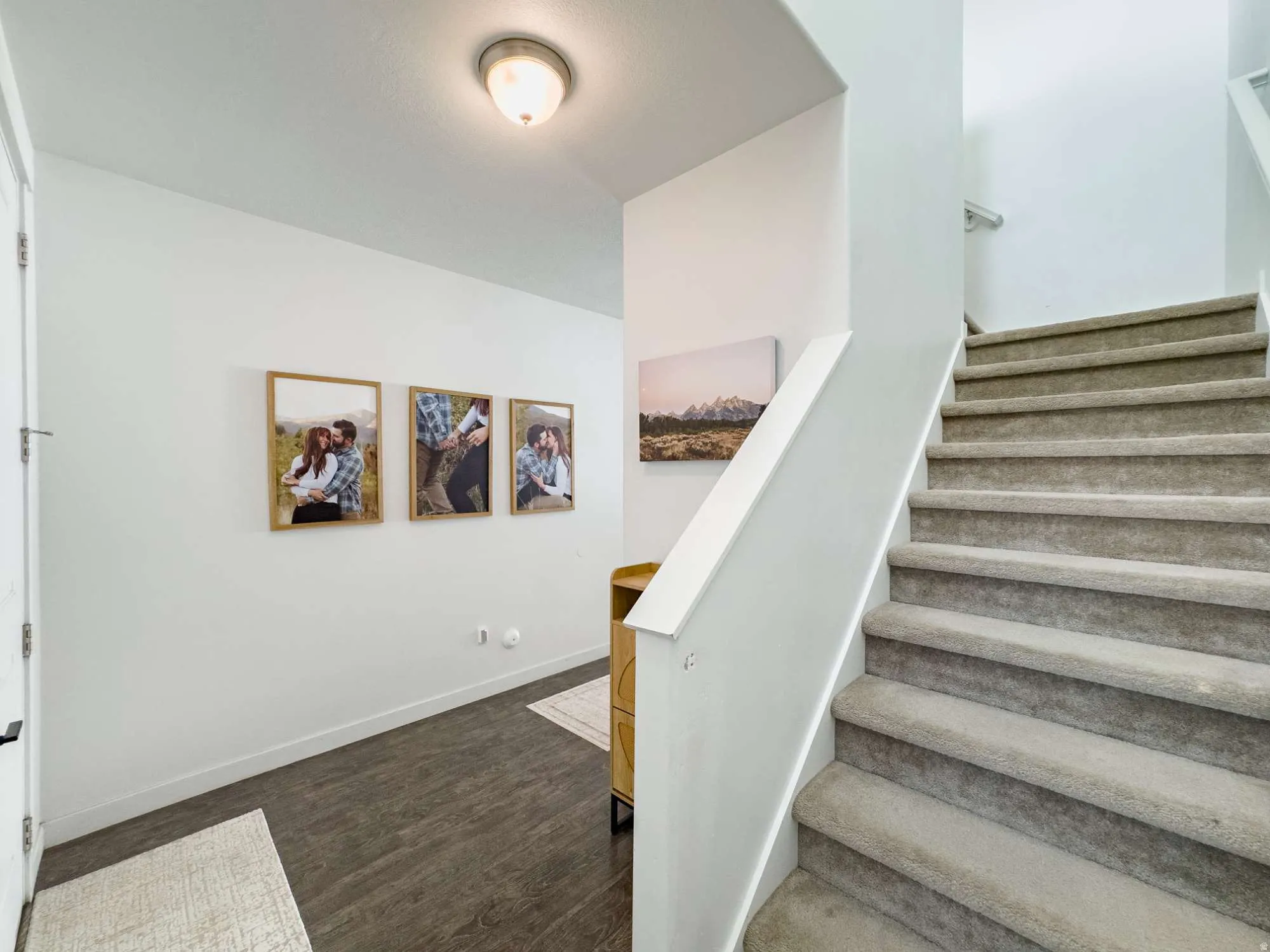 Carpeted staircase featuring a painted handrail and white walls