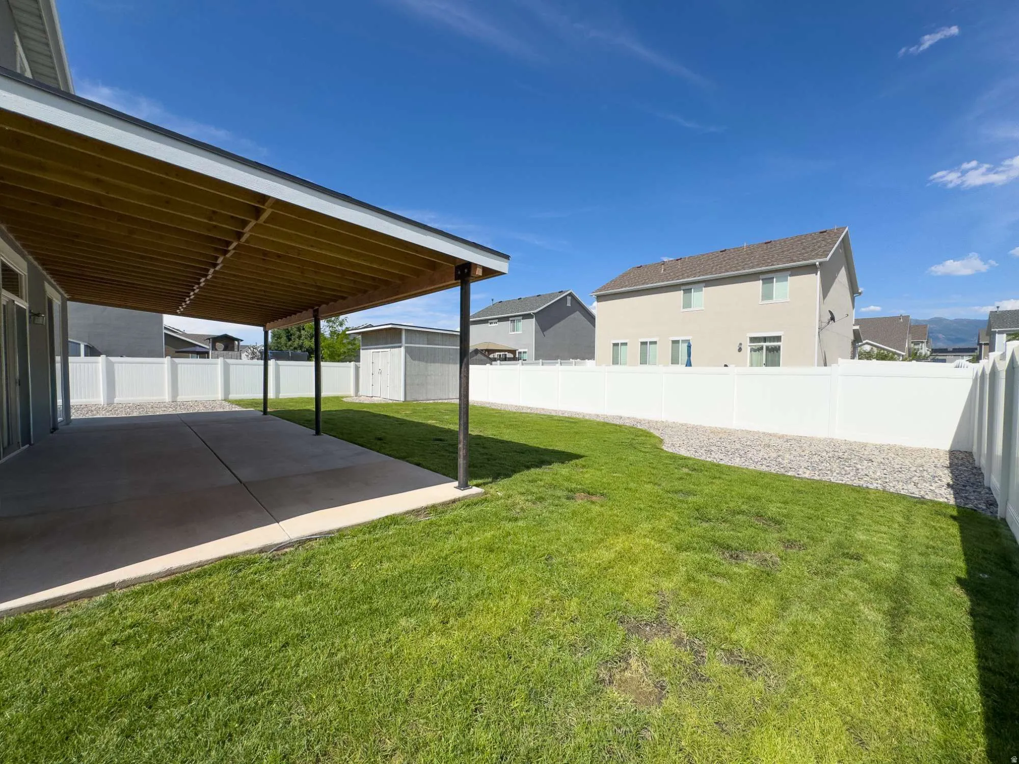 Spacious backyard oasis featuring a manicured lawn, modern metal-frame patio cover with integrated shade structure