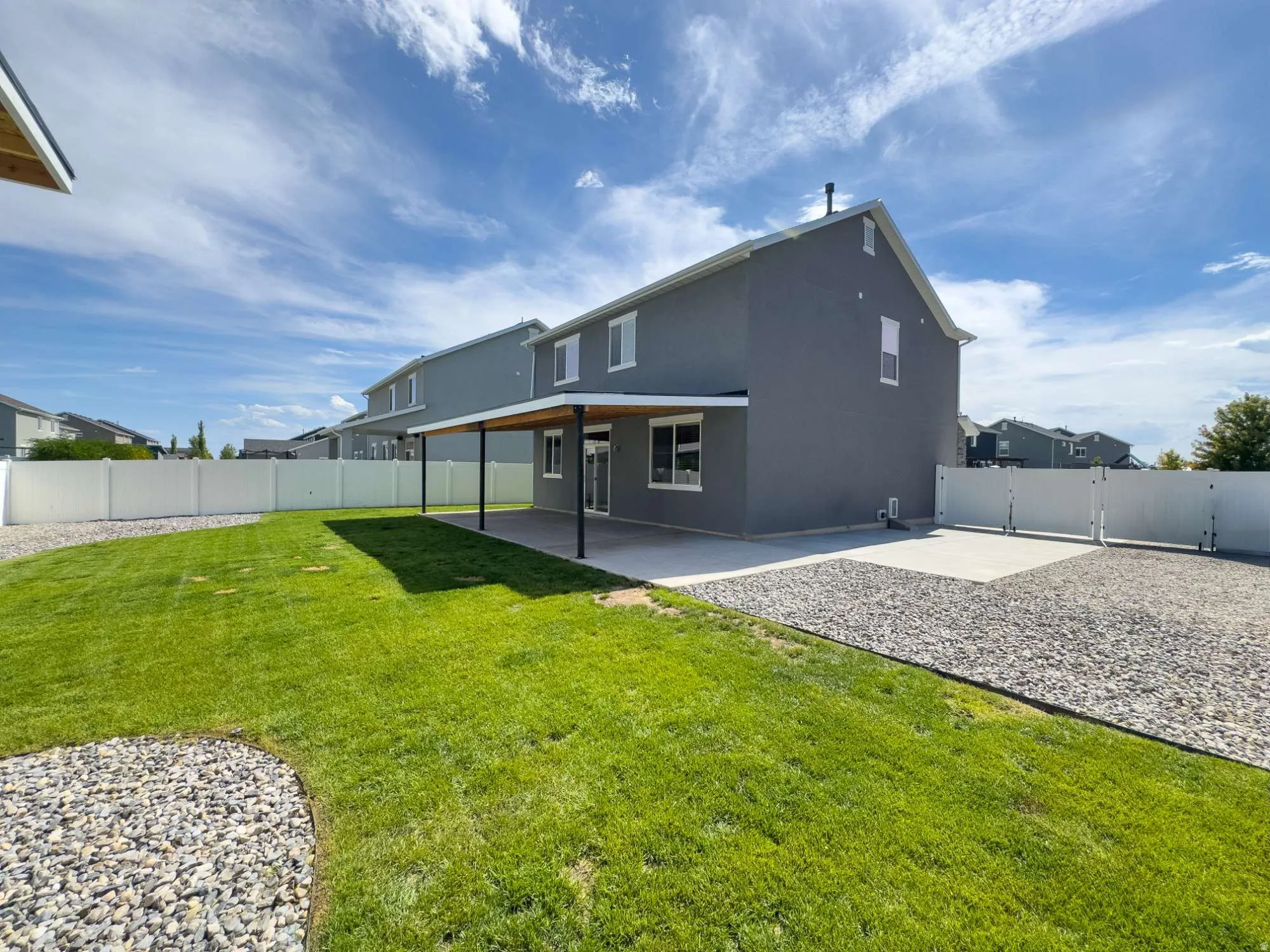 Spacious backyard featuring a large concrete patio with a covered patio
