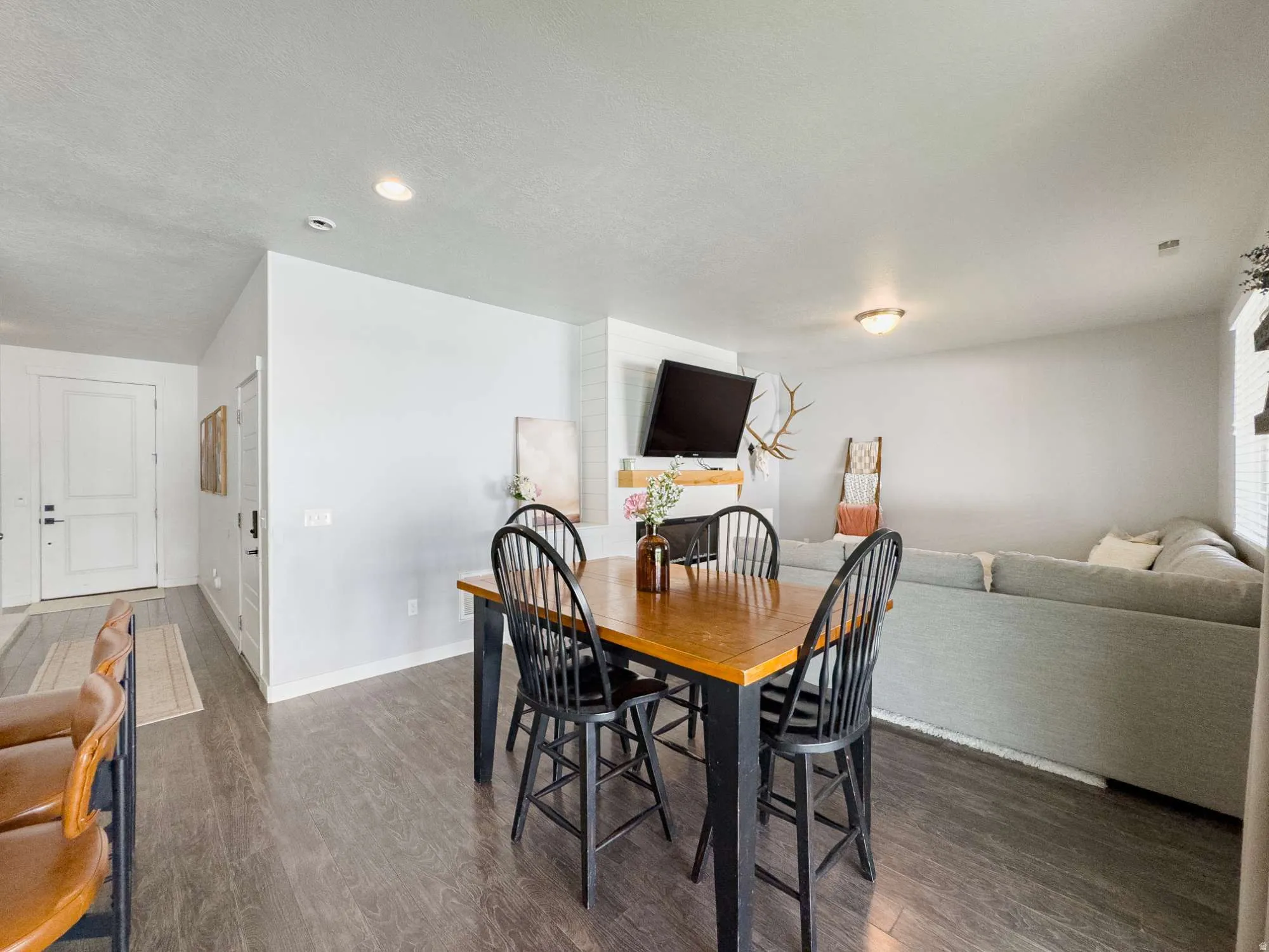 Open-concept dining and living area featuring wood-finish flooring, recessed lighting, and a white fireplace mantel