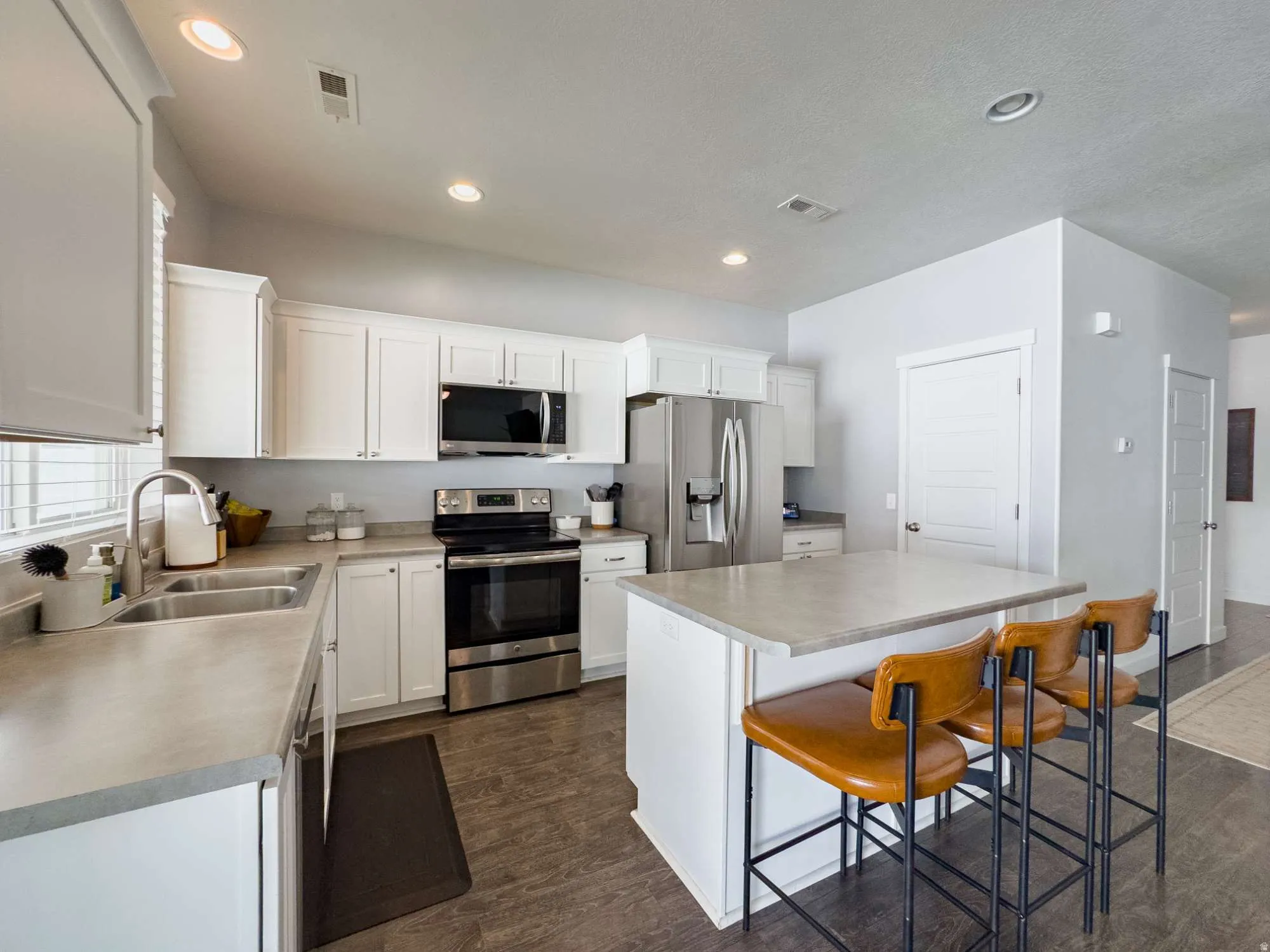 Modern kitchen featuring white cabinetry, stainless steel appliances including a side-by-side refrigerator and convection range