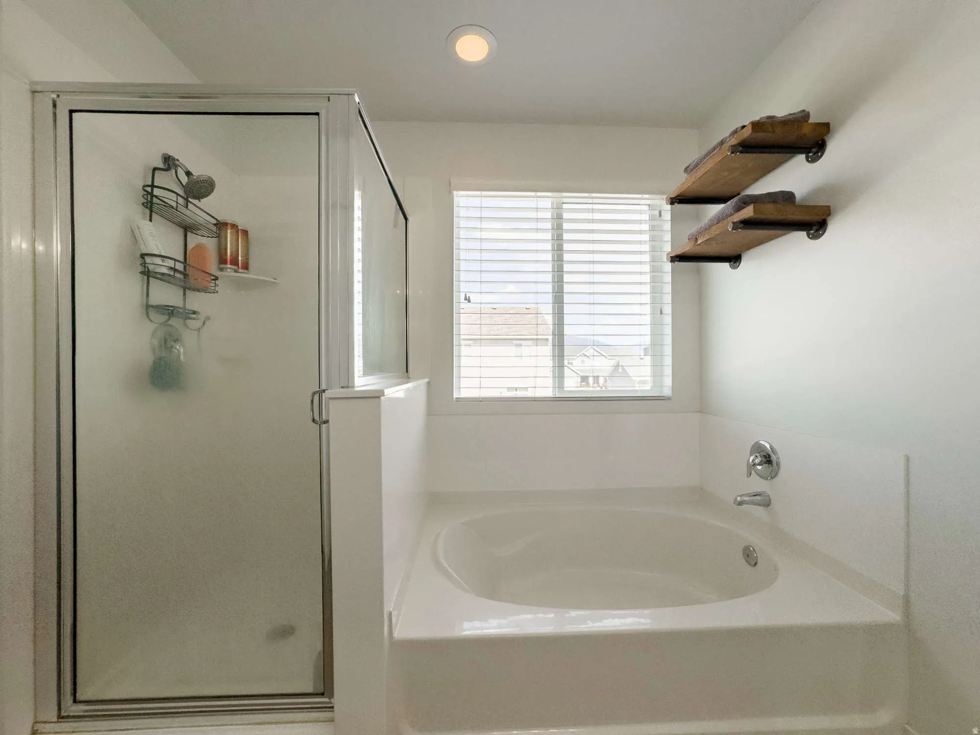 Bathroom featuring an integrated soaking tub, a shower enclosure with a clear glass door