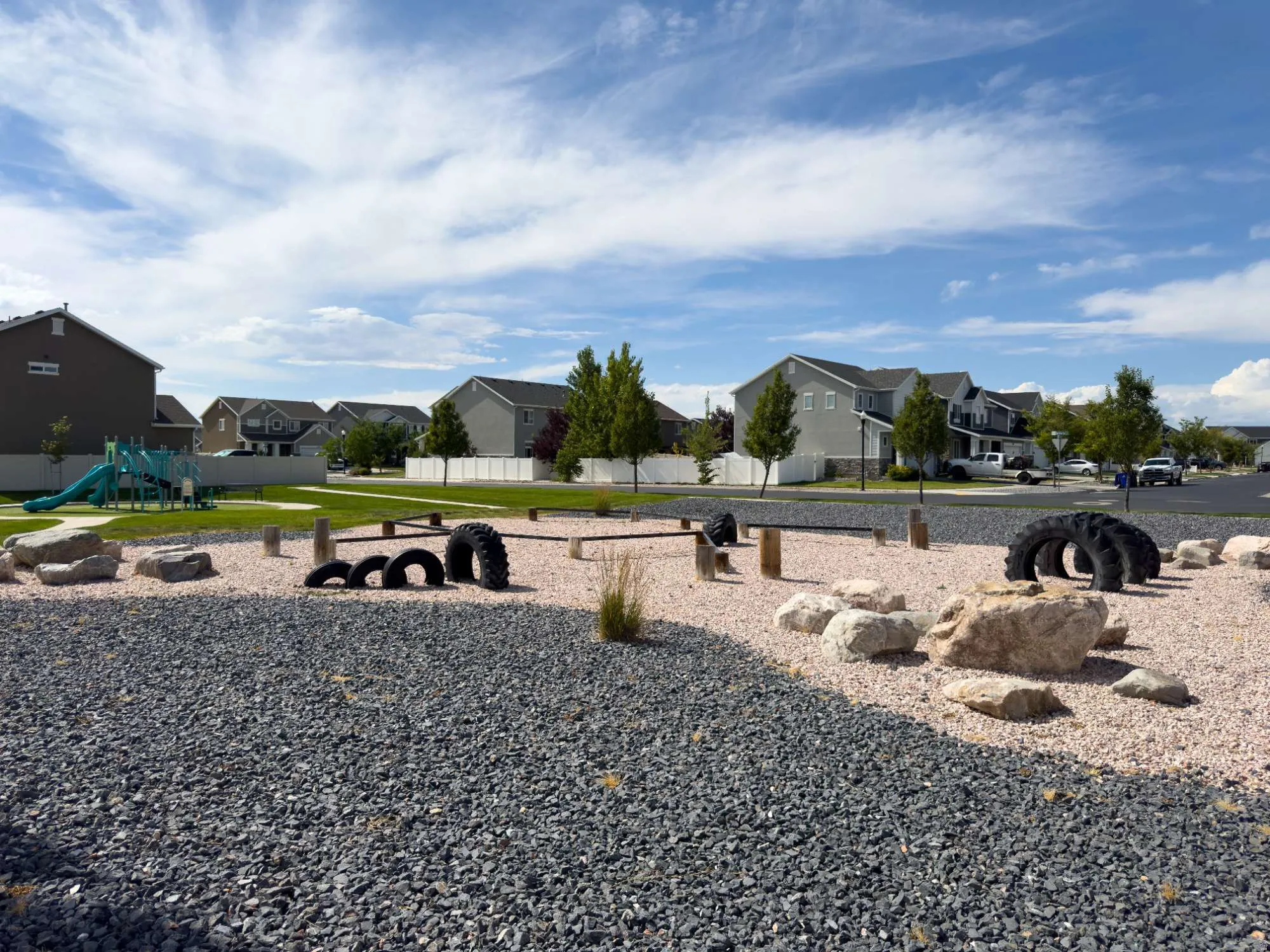 Expansive backyard retreat featuring a gravel landscape with natural stone elements, mature trees, and open lawn space