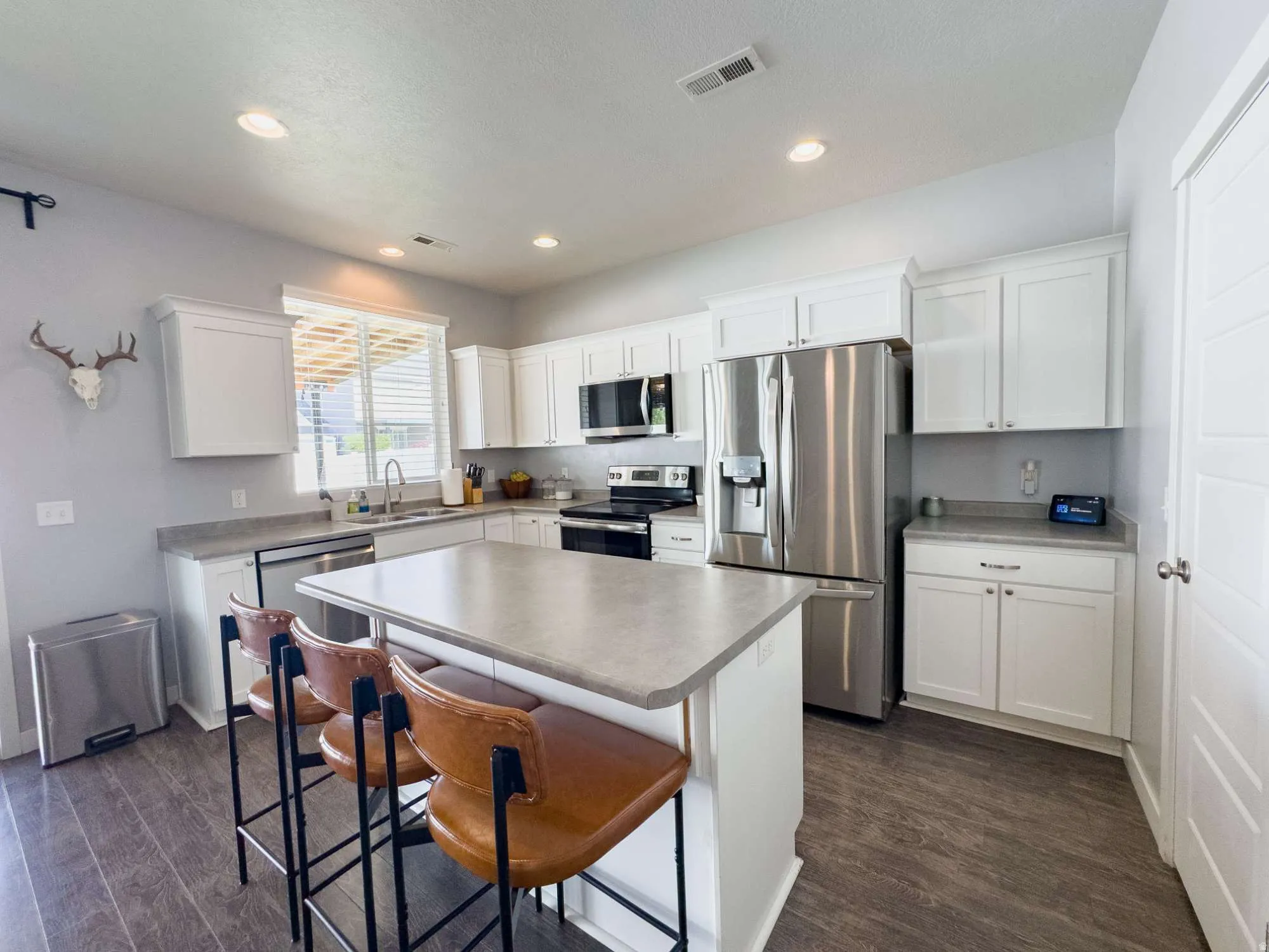 Modern kitchen featuring white cabinetry, stainless steel appliances including a refrigerator, and a gas range