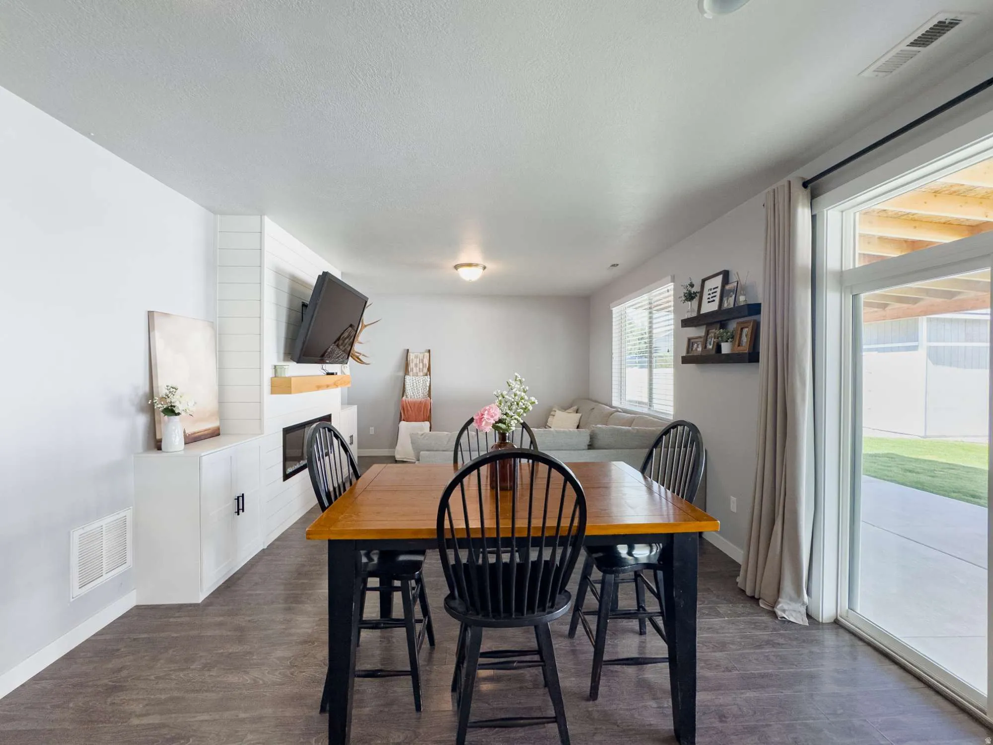 Open-concept living space featuring wood-finish flooring and a built-in fireplace with shiplap detailing