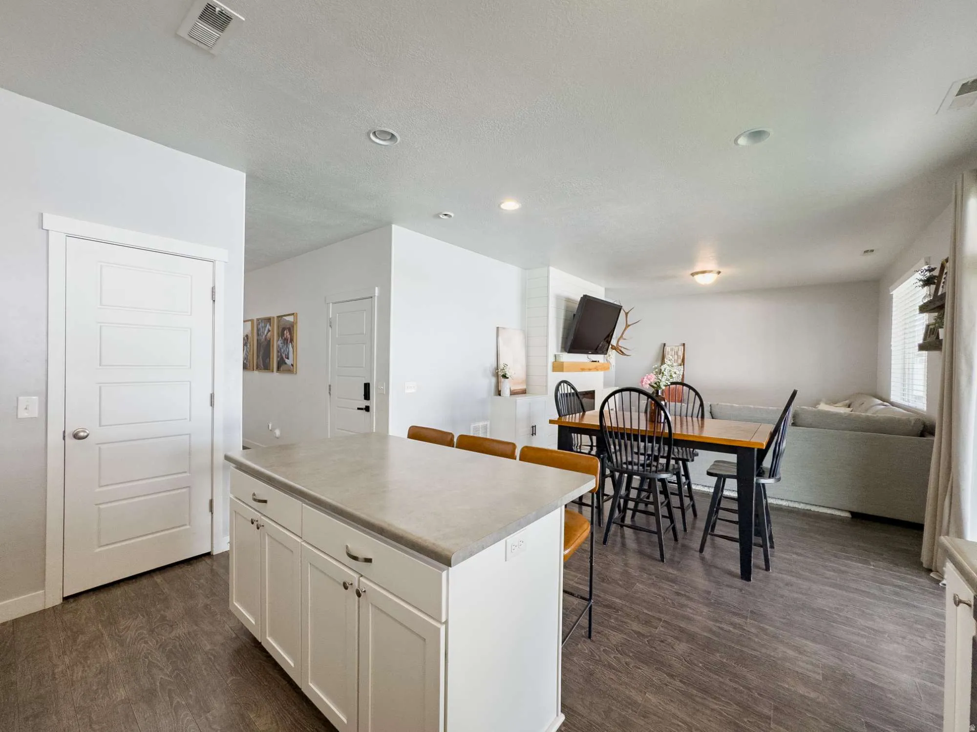 Kitchen island featuring white cabinetry with dark hardware and a light-toned countertop