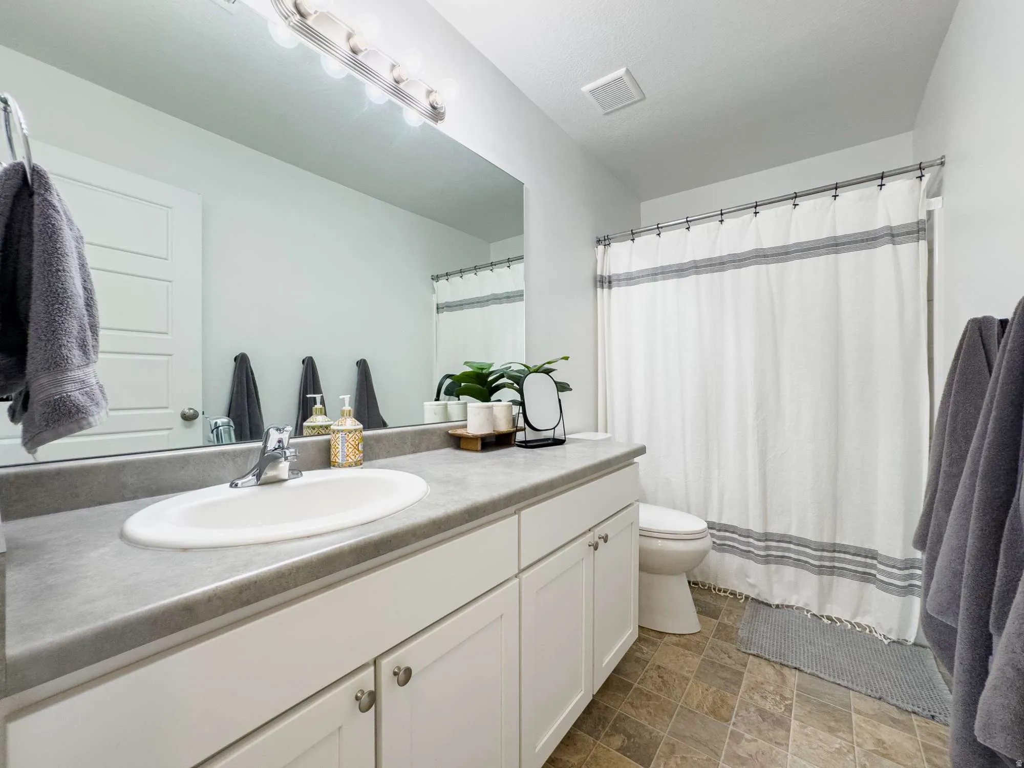 Full secondary bathroom showing sink, commode, and shower.